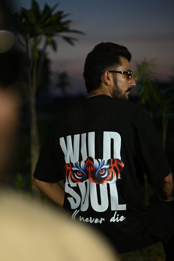 Black oversized t shirt with tiger eyes graphic and bold text “Wild Soul will never die” – streetwear fashion graphic tee for men and women.